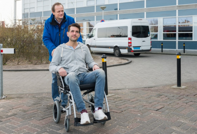 man on wheelchair accompanied be his caregiver
